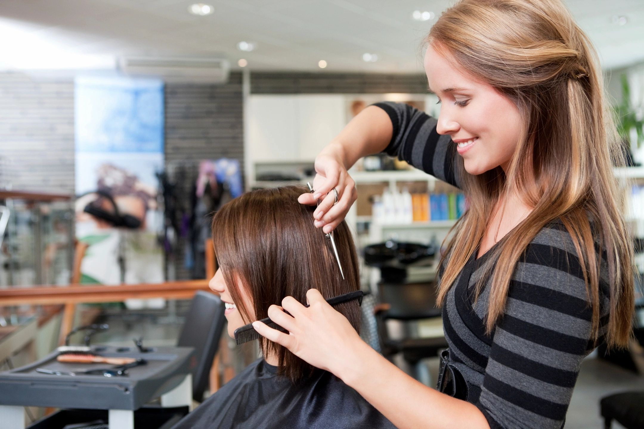 Hairstylist trimming a client’s hair in a bright salon